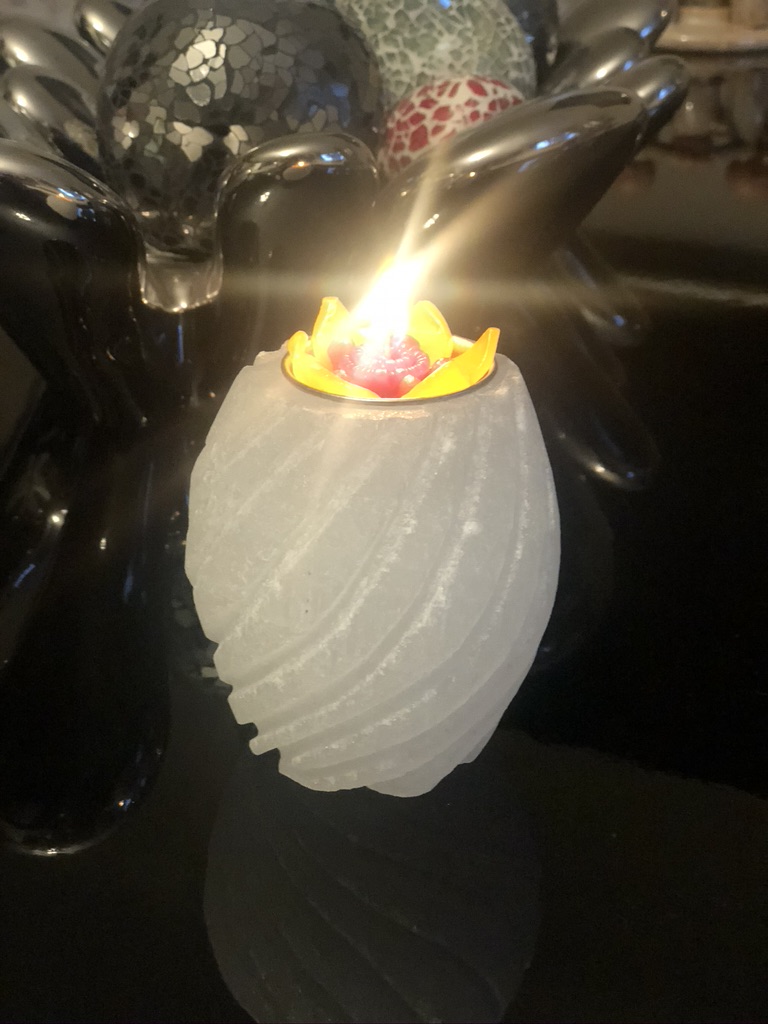 Hand-carved selenite spiral tealight candle holder glowing with soft white crystal light