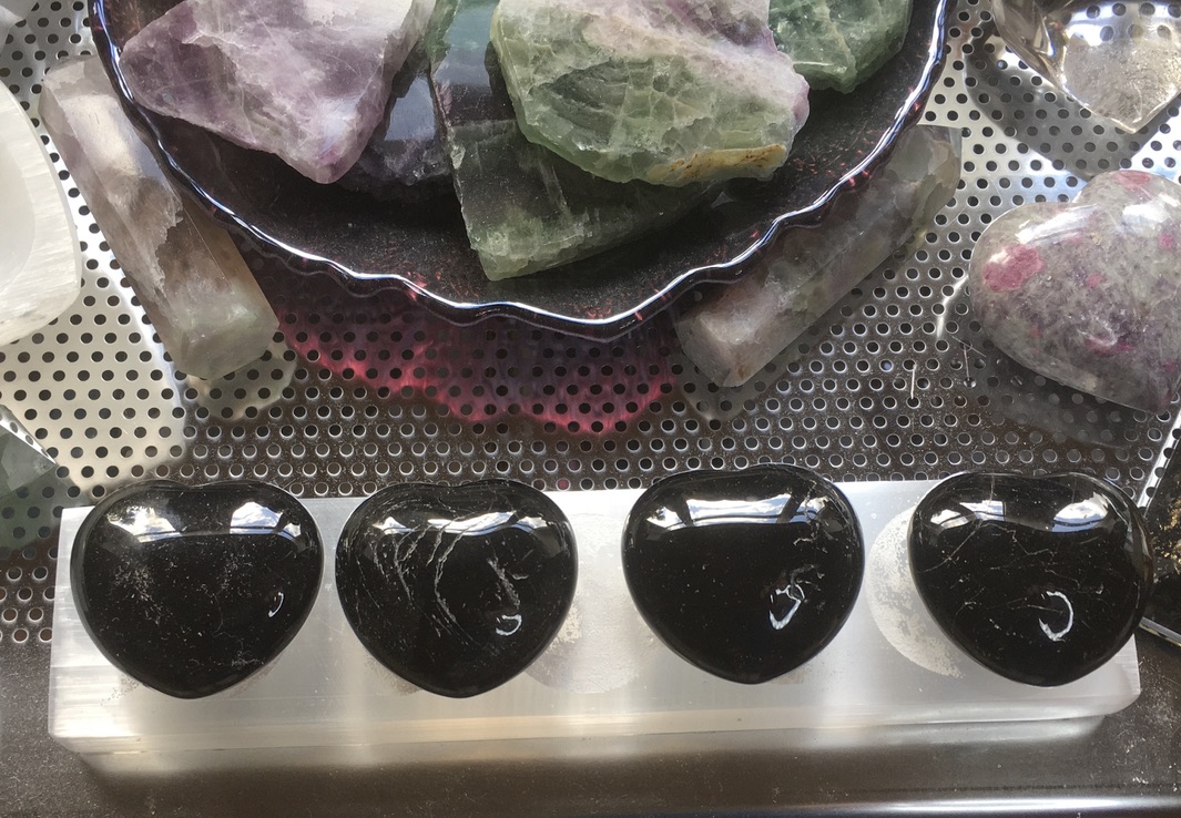 Black tourmaline polished puff hearts on a selenite charging plate