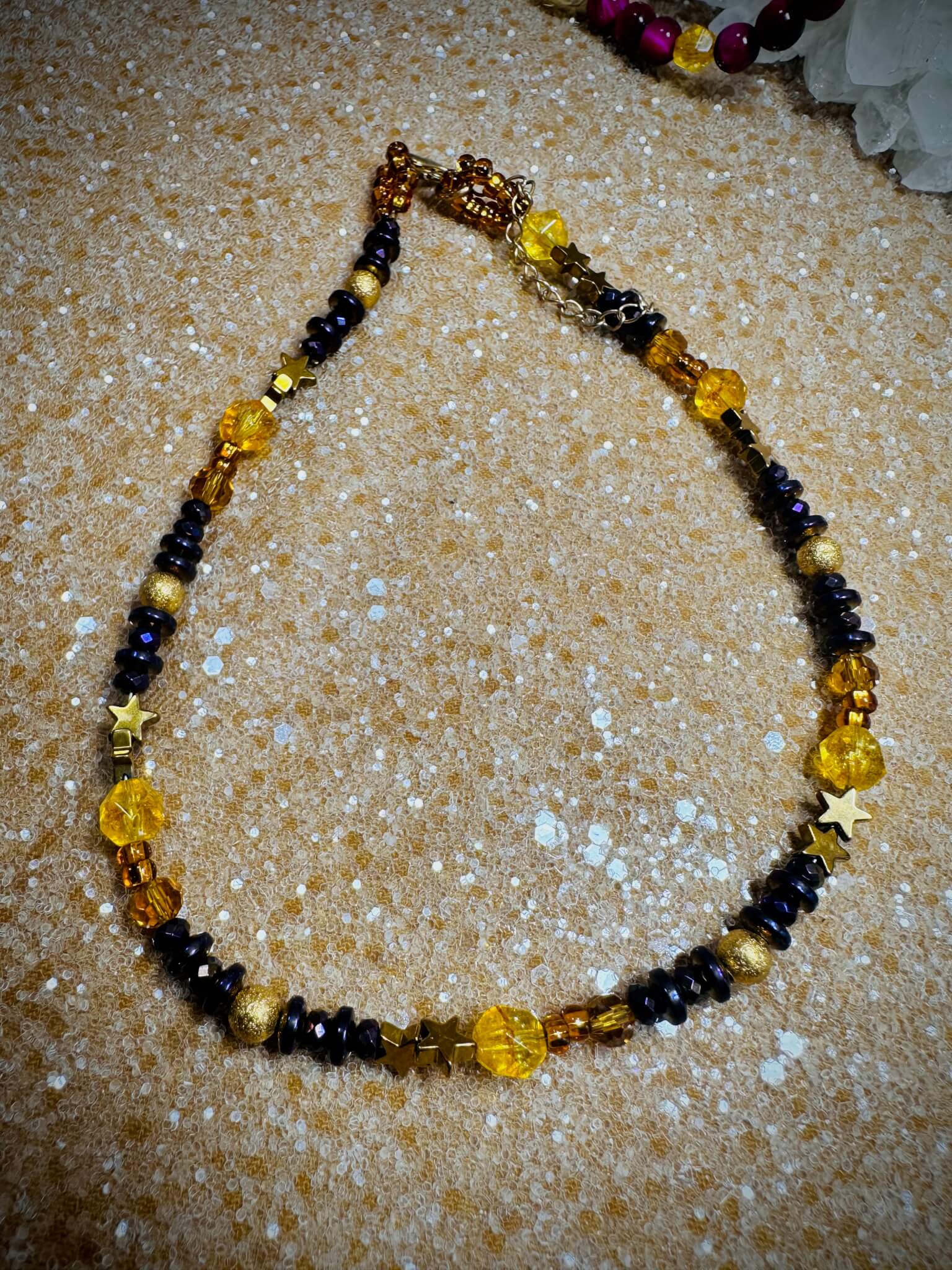 "Radiant Harmony Citrine and Hematite collar necklace laid out on textured gold background."